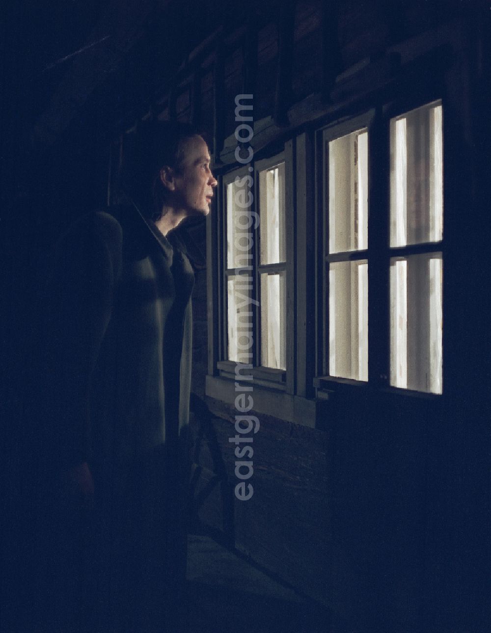 Weißkeißel: Scene from the film and television production Rublak - The Legend of the Surveyed Land in the Haide district of Weisskeissel, Saxony in the area of the former GDR, German Democratic Republic. The actor Christian Grashof stands at the house at night and looks through the window into the farmhouse parlor