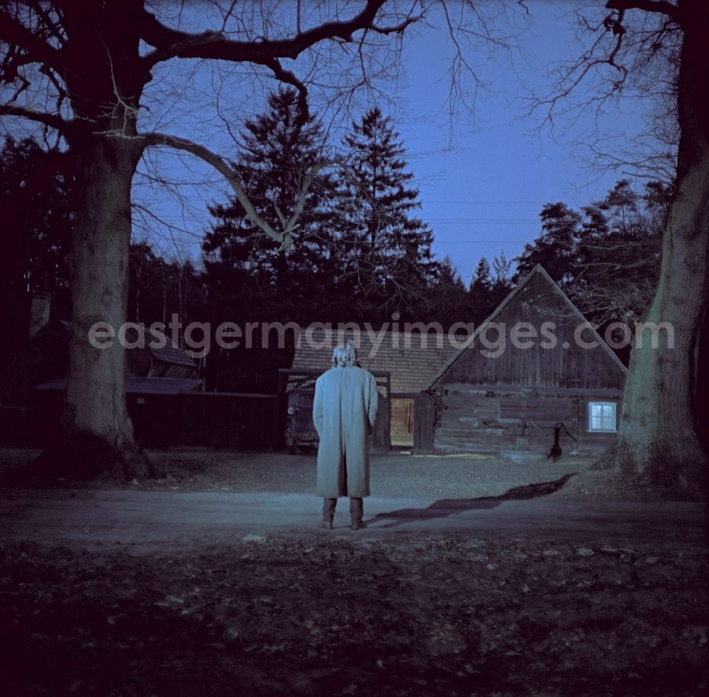 GDR photo archive: Weißkeißel - Scene from the film and television production Rublak - The Legend of the Surveyed Land in the Haide district of Weisskeissel, Saxony in the area of the former GDR, German Democratic Republic. The actor Christian Grashof stands in front of it like a shadow and looks towards the entrance of a farmhouse