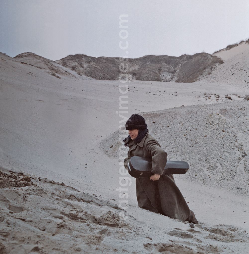 Weißwasser/Oberlausitz: Scene from the film and television production Rublak - The Legend of the Surveyed Land in Weisswasser/Oberlausitz, Saxony in the area of the former GDR, German Democratic Republic. The actor Christian Grashof walks with a violin case under his arm through the sandy plain in the waste landscape of a brown coal open-cast mine