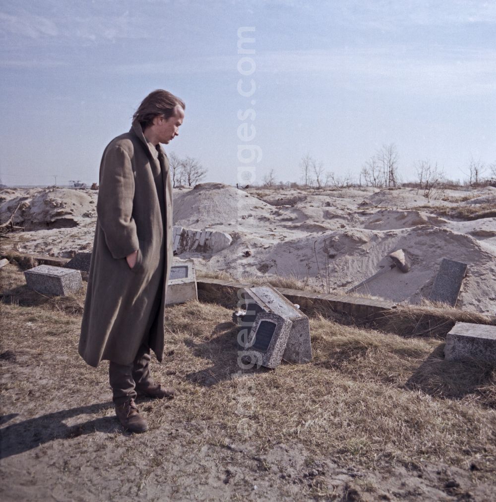 GDR photo archive: Spremberg - Scene from the film and television production Rublak - The Legend of the Surveyed Land Waste landscape in Lusatia - the actor Christian Grashof walks past the destroyed entrance of a cleared cemetery entrance on the street Scene in Spremberg in GDR