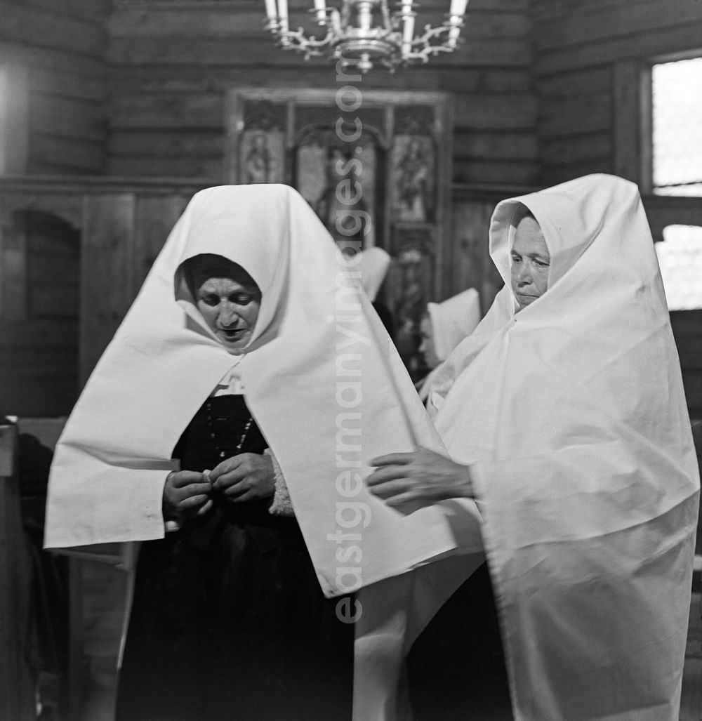 GDR picture archive: Schleife - Scene from the film and television production Struga - Pictures of a Landscape on the street Kirche in Schleife, Saxony in the area of the former GDR, German Democratic Republic. Two Sorbian women putting on mourning clothes in the church in Schleife