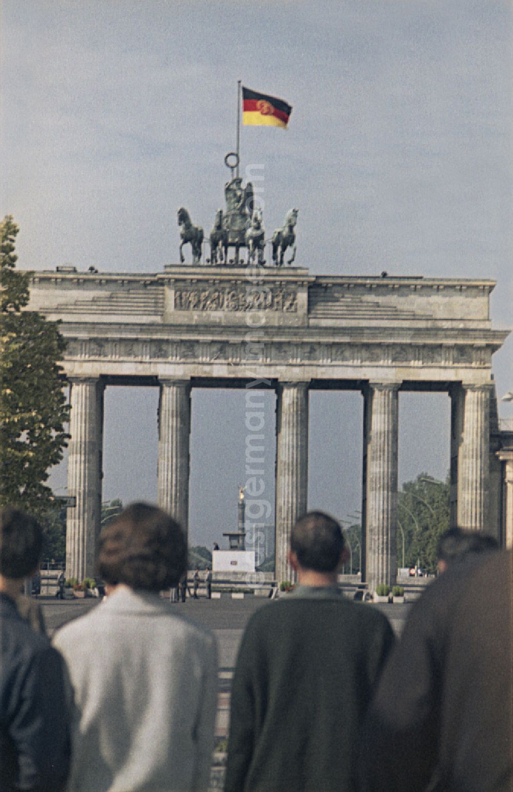 Berlin: Tourist attraction and landmark Brandenburg Gate with Quadriga and GDR flag in the border area of the Wall and state border at Pariser Platz - Unter den Linden in the Mitte district of Berlin East Berlin on the territory of the former GDR, German Democratic Republic