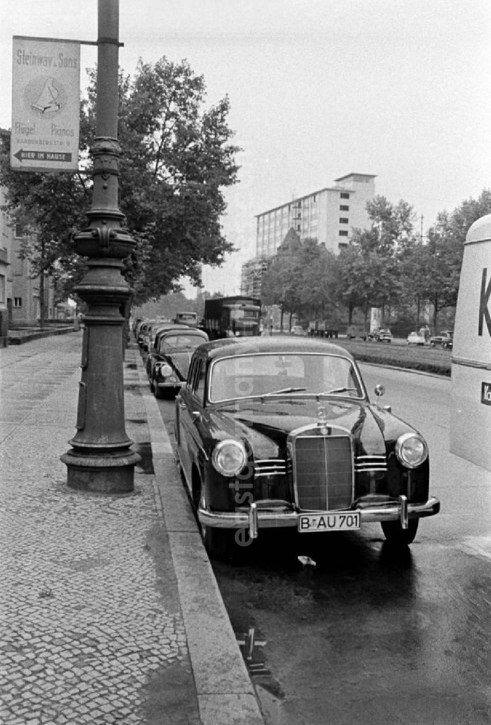 GDR picture archive: Berlin - Ein Mercedes parkt in der Hardenbergstraße in Westberlin. Das Nummernschild deutet auf die gerade stattfindende Interbau, die Internationale Bauausstellung in Berlin. Das Werbeschld an der Laterne wirbt für das traditionelle Unternehmen Steinway. Im Hintergrund werden gerade die Fakultätsgebäude der Technischen Universität Berlin am Ernst-Reuter-Platz gebaut. In den 5