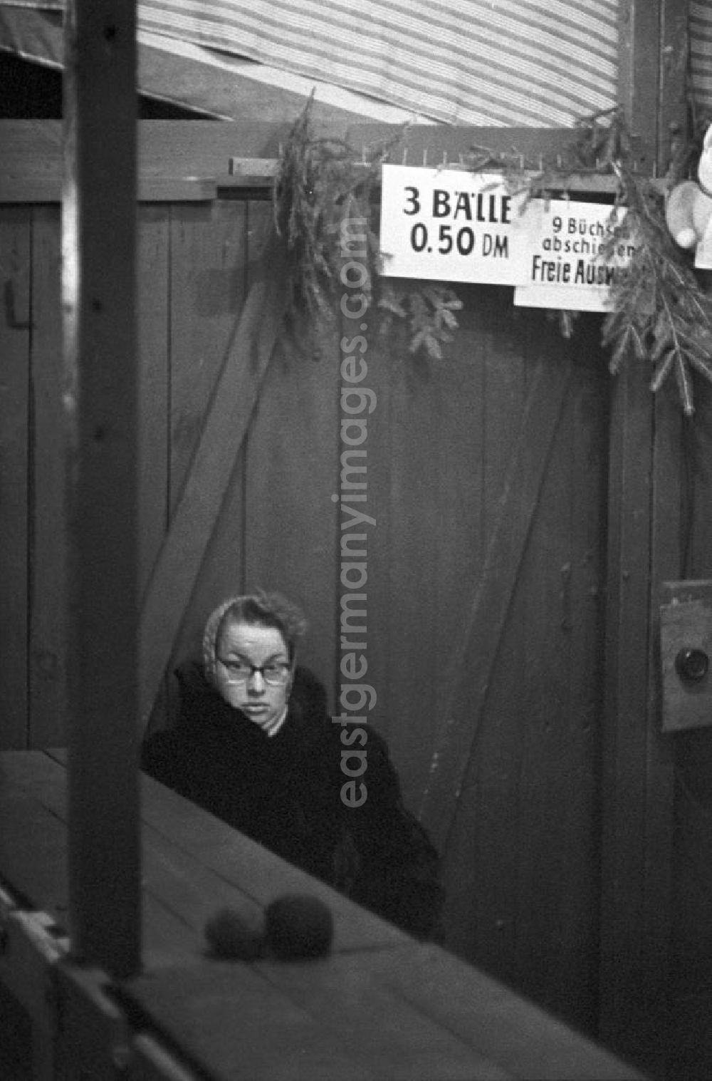 GDR photo archive: Leipzig - Eine Frau sitzt auf dem Leipziger Weihnachtsmarkt hinter der Theke einer Bude für Büchsenwerfen und wartet auf Kundschaft. Im Hintergrund zwei Schilder mit der Aufschrift 3 Bälle 0,5