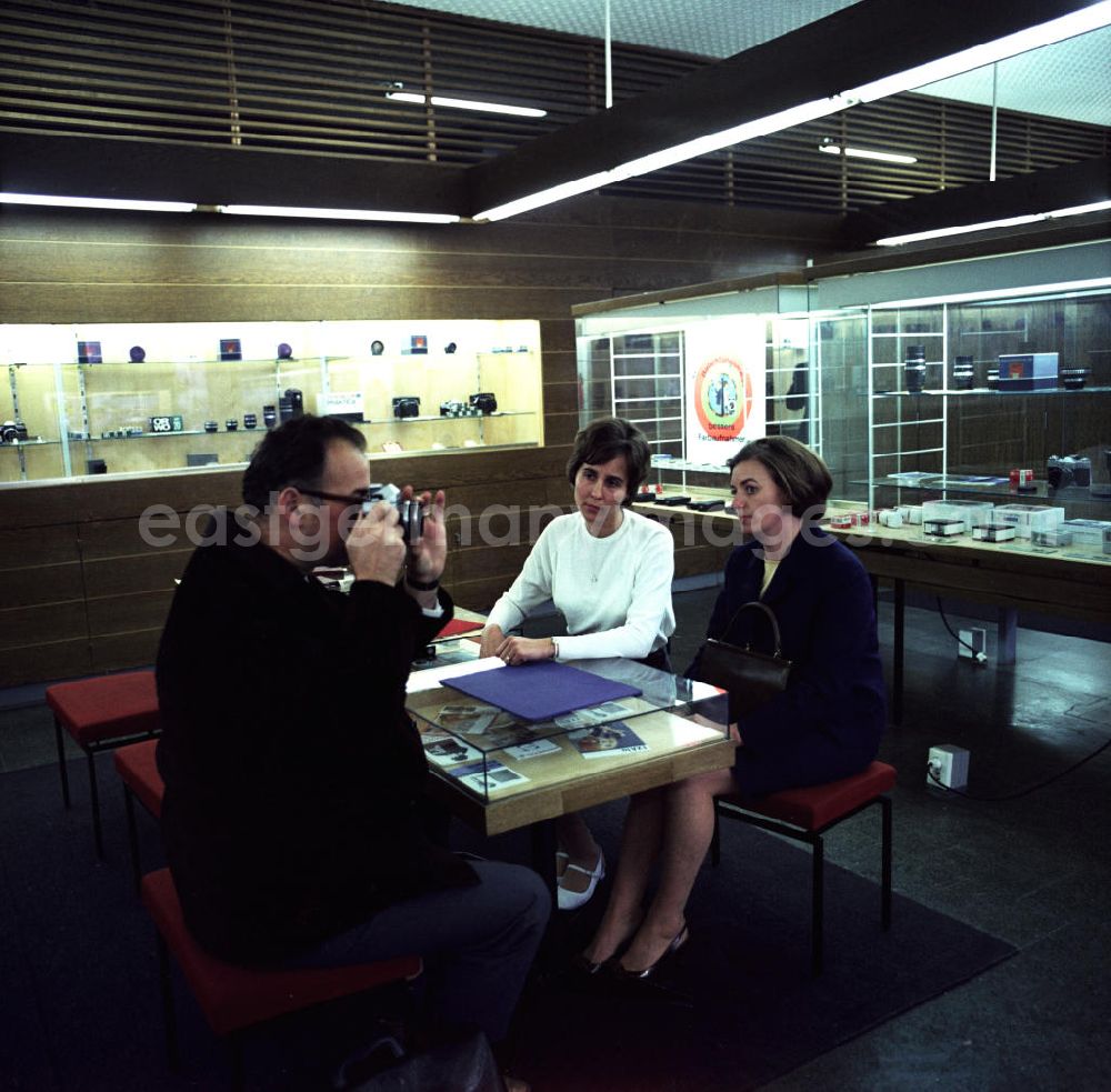 GDR image archive: Berlin - Verkaufsgespräch im Fotofachgeschäft des Kombinates Zeiss am Alexanderplatz in Berlin Mitte. Kunden interessieren sich für eine Kleinbildkamera der Marke Praktika.