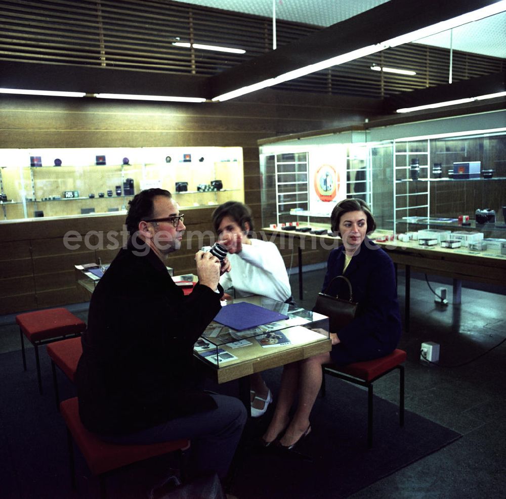 GDR photo archive: Berlin - Verkaufsgespräch im Fotofachgeschäft des Kombinates Zeiss am Alexanderplatz in Berlin Mitte. Kunden interessieren sich für eine Kleinbildkamera der Marke Praktika.