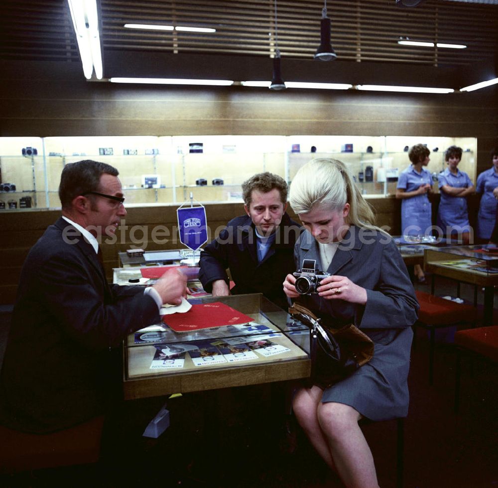 GDR image archive: Berlin - Verkaufsgespräch im Fotofachgeschäft des Kombinates Zeiss am Alexanderplatz in Berlin Mitte. Kunden interessieren sich für eine Kleinbildkamera der Marke Praktika.