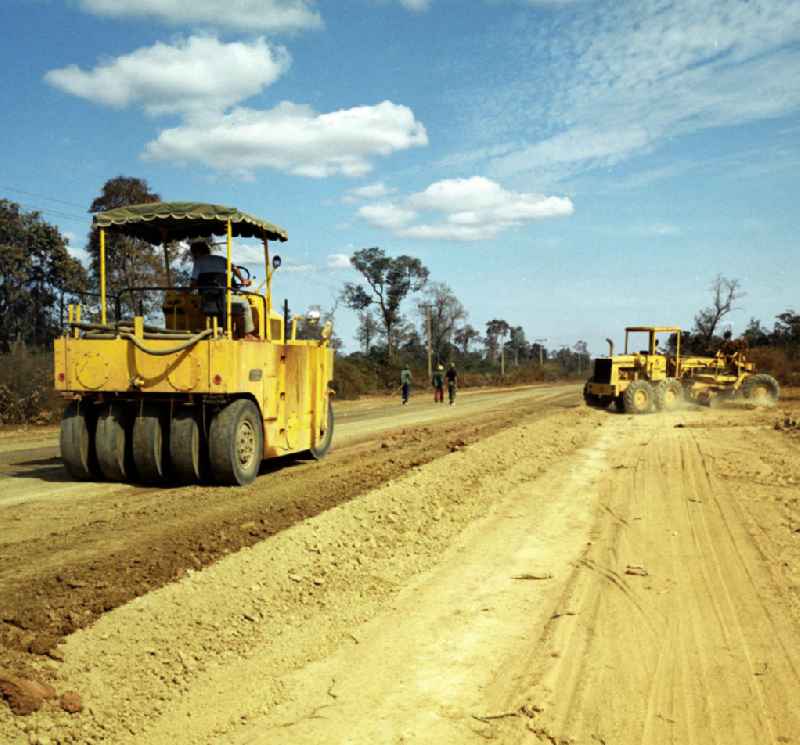 Einsatz von US-amerikanischen Baumaschinen, hier eine Gummiradwalze und ein Grader, für den Straßenbau in der Demokratischen Volksrepublik Laos.