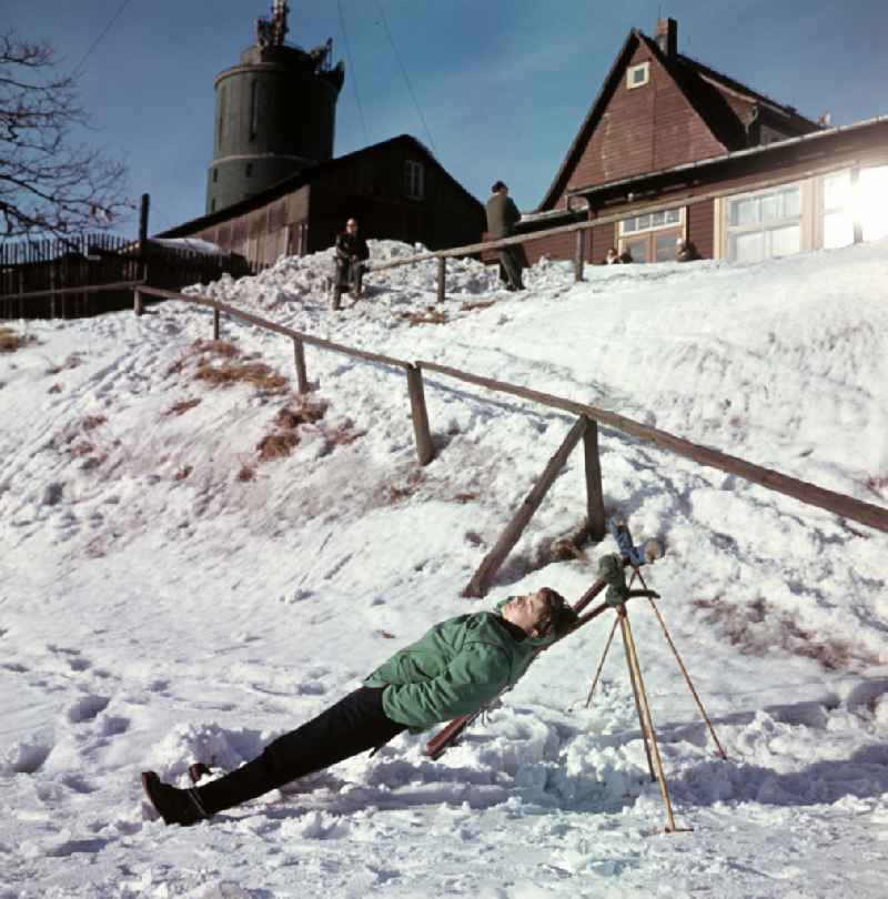 Sunbathing on skis on the Grosser Inselsberg with transmission tower in winter in Bad Tabarz, Thuringia in the territory of the former GDR, German Democratic Republic