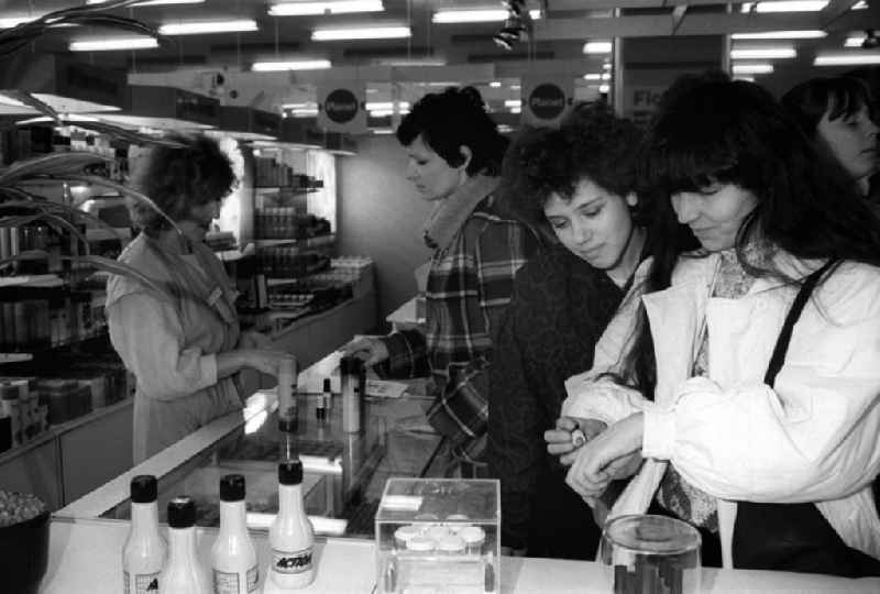 Frauen stehen am Verkaufstresen und testen in der Kosmetikabteilung vom Centrum-Warenhaus am Alexanderplatz Kosmetikprodukte. Im Hintergrund berät eine Verkäuferin eine Kundin.