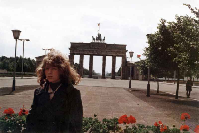 Eine Frau steht auf dem Pariser Platz vor dem Brandenburger Tor auf der Seite von Ostberlin mit der Mauer im Hintergrund. Ein Soldat / Grenzsoldat (r) schaut der Frau und dem Fotografen zu. Das Brandenburger Tor ist ein Symbol für die Teilung von Deutschland bzw. Berlin.