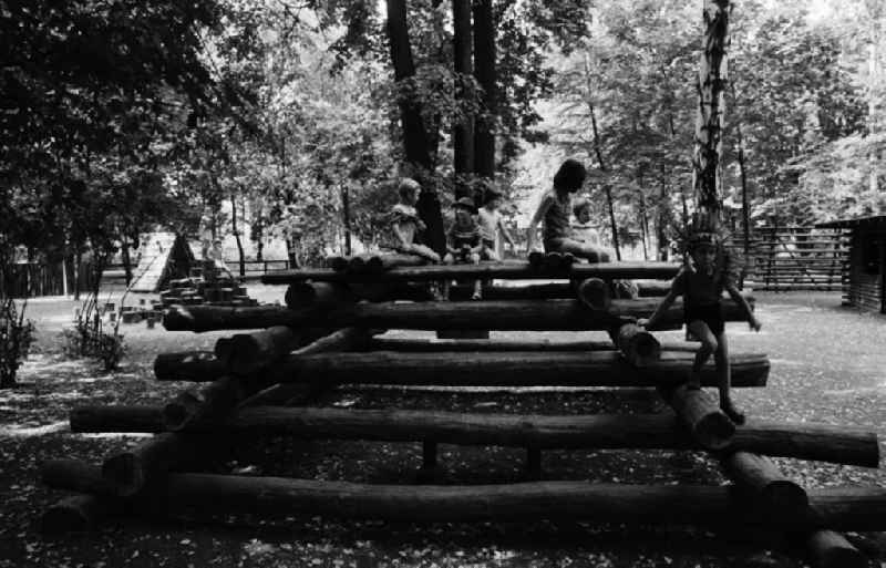 Kinder spielen auf dem Indianerspielplatz / Abenteuerspielplatz im Biesdorfer Park in Berlin-Lichtenberg. Ein Kind trägt Indianerschmuck auf dem Kopf.