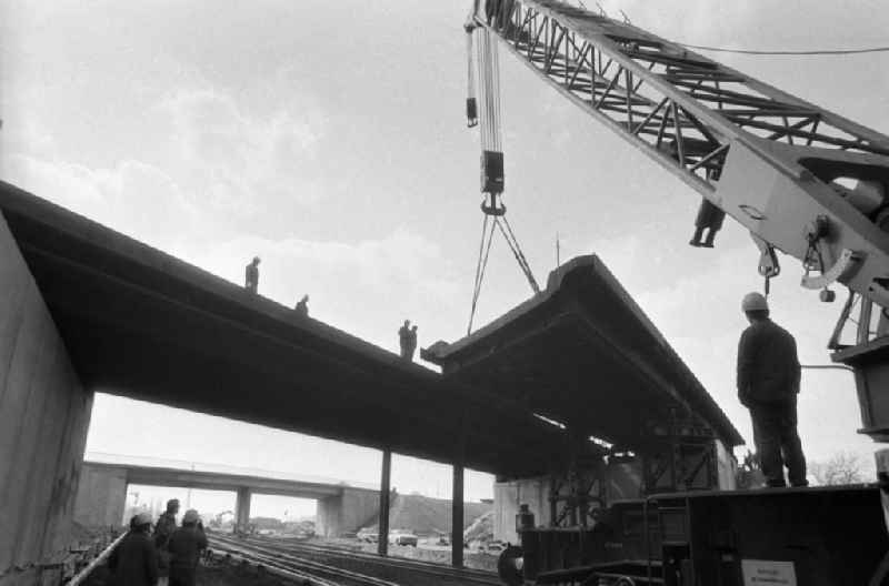 Brückenarbeiten in Marzahn an der Berliner Chaussee. Brückenstück hängt am Kran, Bauarbeiter schauen zu.
