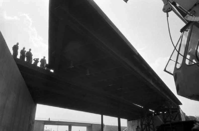 Brückenarbeiten in Marzahn an der Berliner Chaussee. Blick vorbei am Kran auf die fast fertigtgestellte Brücke. Bauarbeiter stehen auf Brücke.