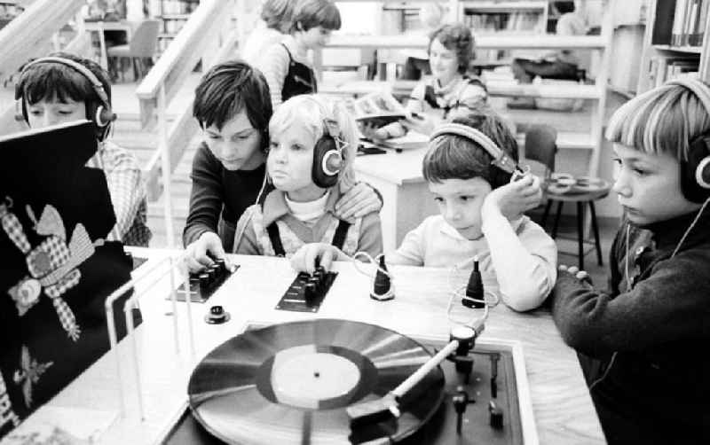 Kinder hören sich in einer Kinderbücherei / Bibliothek Langspielplatten / Schallplatten an.