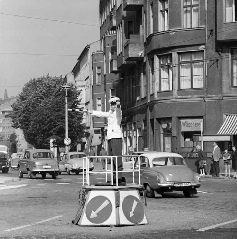 Eine Ampel gibt es hier noch nicht. Junge Verkehrspolizisten nehmen am Rosenthaler Platz an einem Wettstreit zur manuellen Verkehrsregelung teil. Rechts am Straßenrand der zugemauerte Eingang in eine U-Bahnstation, die nur von Bahnen aus dem Westteil der Stadt ohne Halt passiert wird.