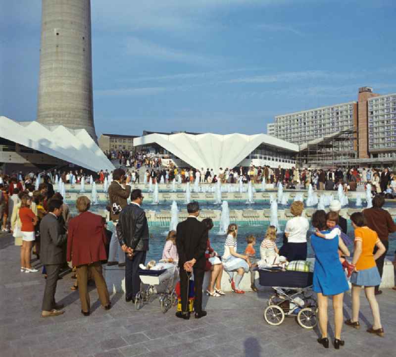 Bei Jung und Alt beliebt waren die Wasserspiele am Fuße des Berliner Fernsehturms. Im Hintergrund die Fußumbauung des Fernsehturms mit dem Ausstellungspavillon unter dem Faltendach. Mit der Errichtung des Fernsehturms sowie der Umgestaltung seiner Umgebung war das historische Stadtzentrum zwecks Baufreimachung 'bereinigt' worden - der ursprüngliche aus dem Mittelalter stammende Stadtgrundriß mußte mit Ausnahme der Marienkirche und des Roten Rathauses der sozialistischen Stadtplanung weichen.