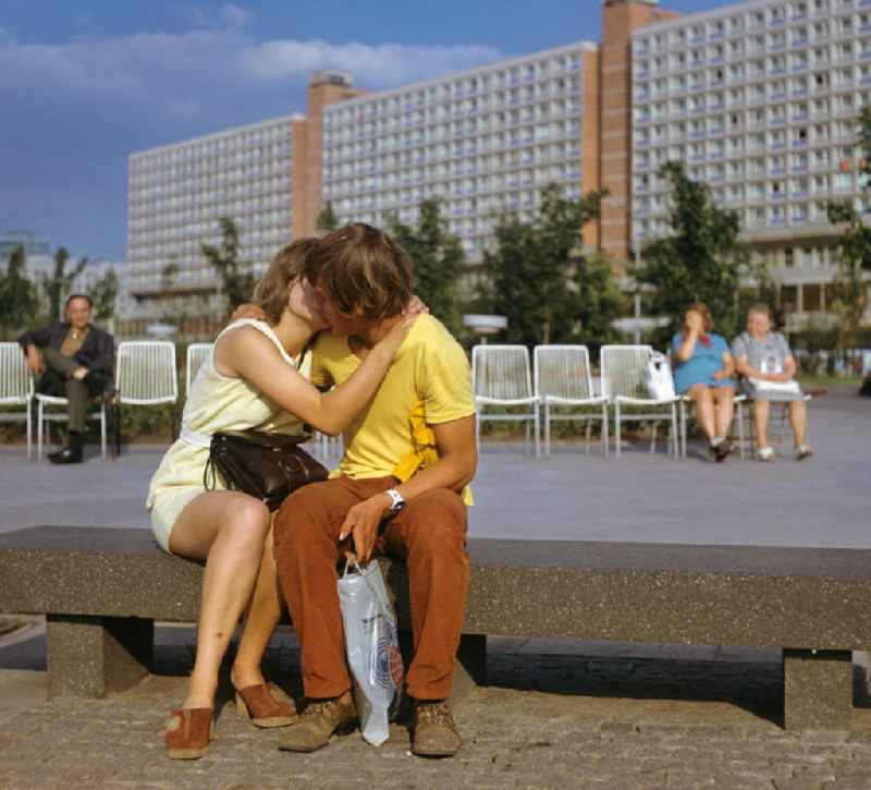 Zu den Weltfestspielen im Sommer 1973 in Berlin sitzt ein junges Paar in der Parkanlage am Neptunbrunnen nahe dem Berliner Fernsehturm auf einer Steinbank und küßt sich.