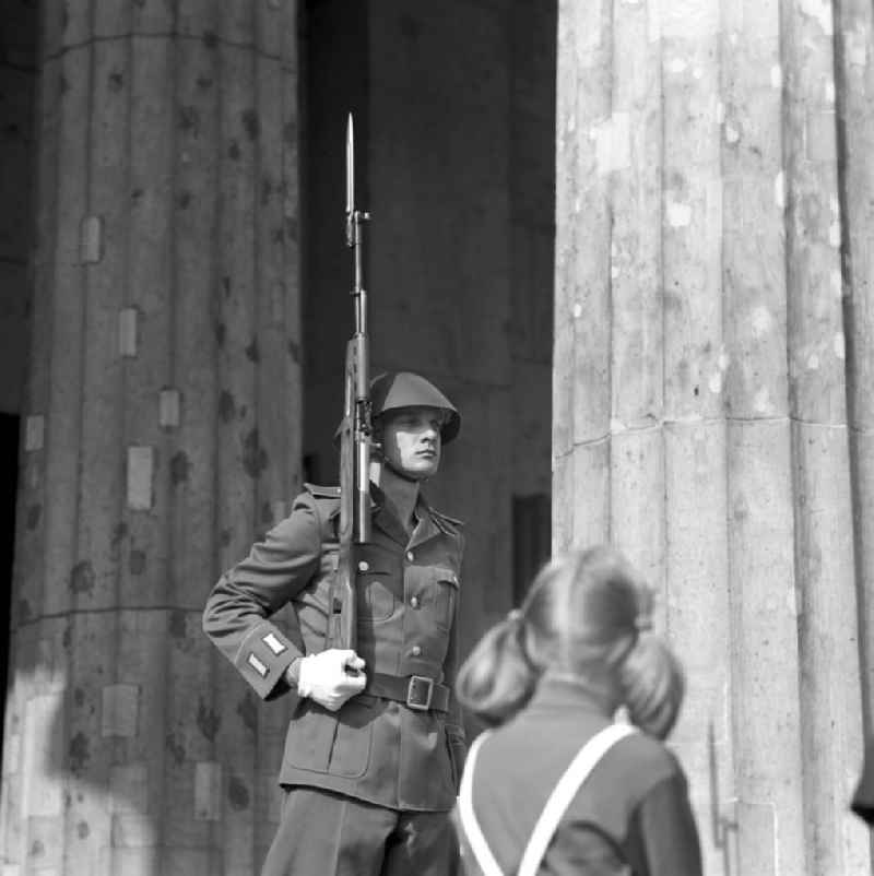 Ein Mädchen betrachtet einen vor der Neuen Wache Unter den Linden in Berlin postierten NVA-Soldaten. Die ständige Ehrenwache der Nationalen Volksarmee stand an dem historischen Bau, der zu DDR-Zeiten als zentrale Gedenkstätte für die Opfer des Faschismus und Militarismus eingerichtet war.