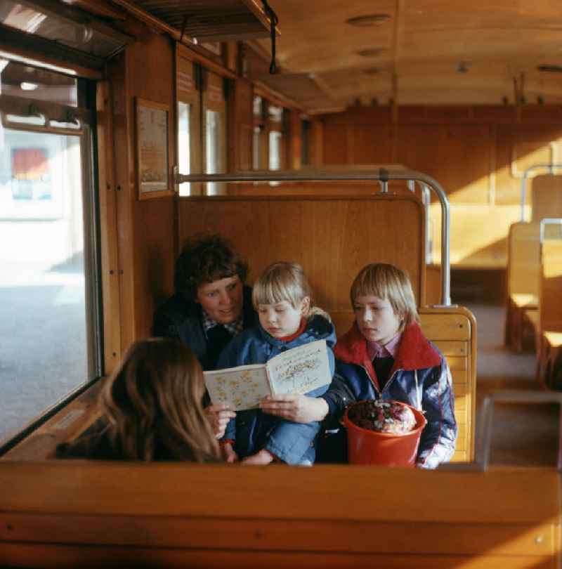 Eine Familie liest in einer Berliner S-Bahn das Buch 'Ferdinand, der Stier' von Munro Leaf.