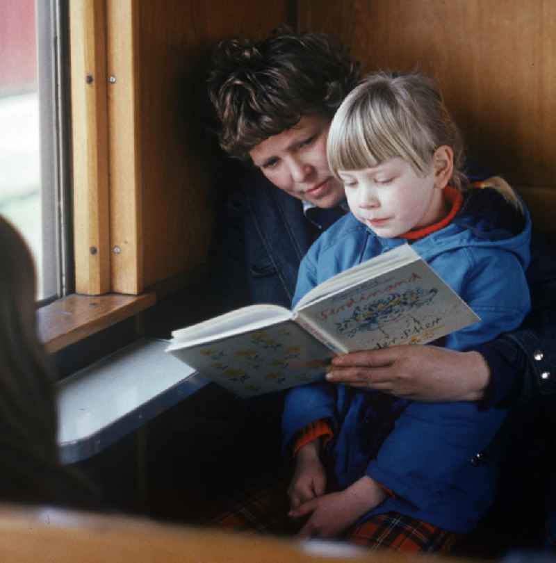 Eine Frau liest mit ihrer Tochter in einer Berliner S-Bahn das Buch 'Ferdinand, der Stier' von Munro Leaf.