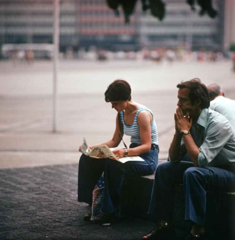 Eine Frau liest auf dem Alexanderplatz in Berlin-Mitte ihre Zeitung.