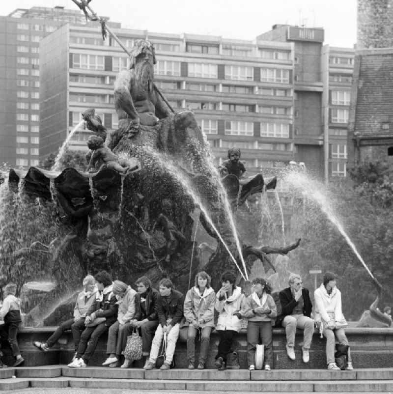 Besucher des ND-Pressefestes sitzen auf dem Rand des Neptunbrunnens in Berlin-Mitte. Der Neptunbrunnen war im Jahr 1969 auf der großen Freifläche neben der Marienkirche (r) im Schnittpunkt der Achsen zwischen Fernsehturm und Rathaus wiederaufgestellt worden, nachdem er 1951 von seinem ursprünglichen Standort vor dem Stadtschloss nach dessen Sprengung abgetragen und eingelagert worden war.