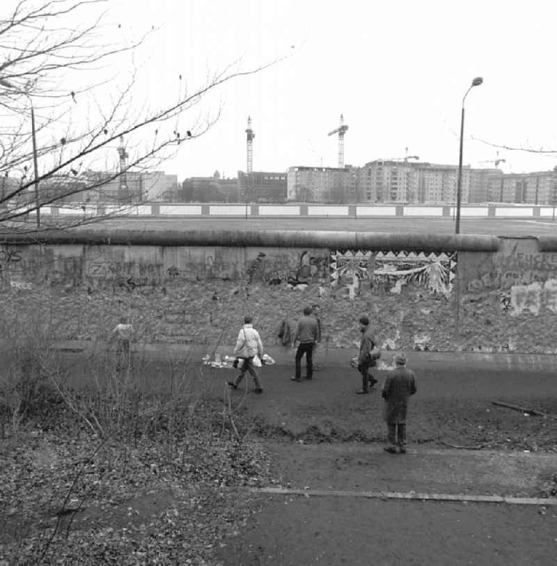View at the system boundary of the Berlin Wall between Ebert Strasse and Wilhelmstrasse in Berlin. People walking at the Berlin Wall on the West Berlin side