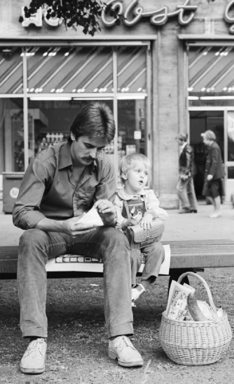 A father sitting with his child on a bench in the Karl-Marx-Allee in Berlin, the former capital of the GDR, the German Democratic Republic