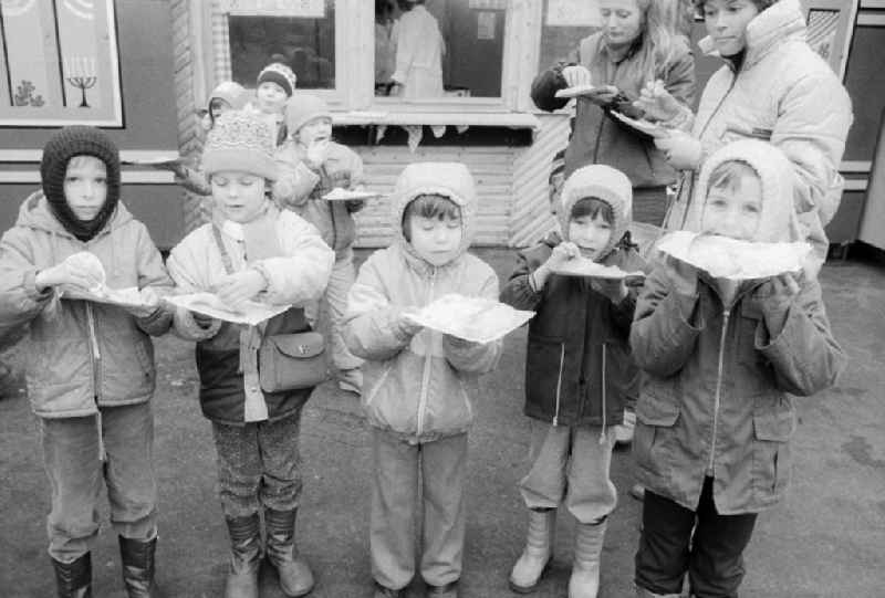 Children eat full pancakes on the Berlin Christmas fair in Berlin, the former capital of the GDR, German democratic republic. Today there stands at this point the shopping centre 'Alexa'