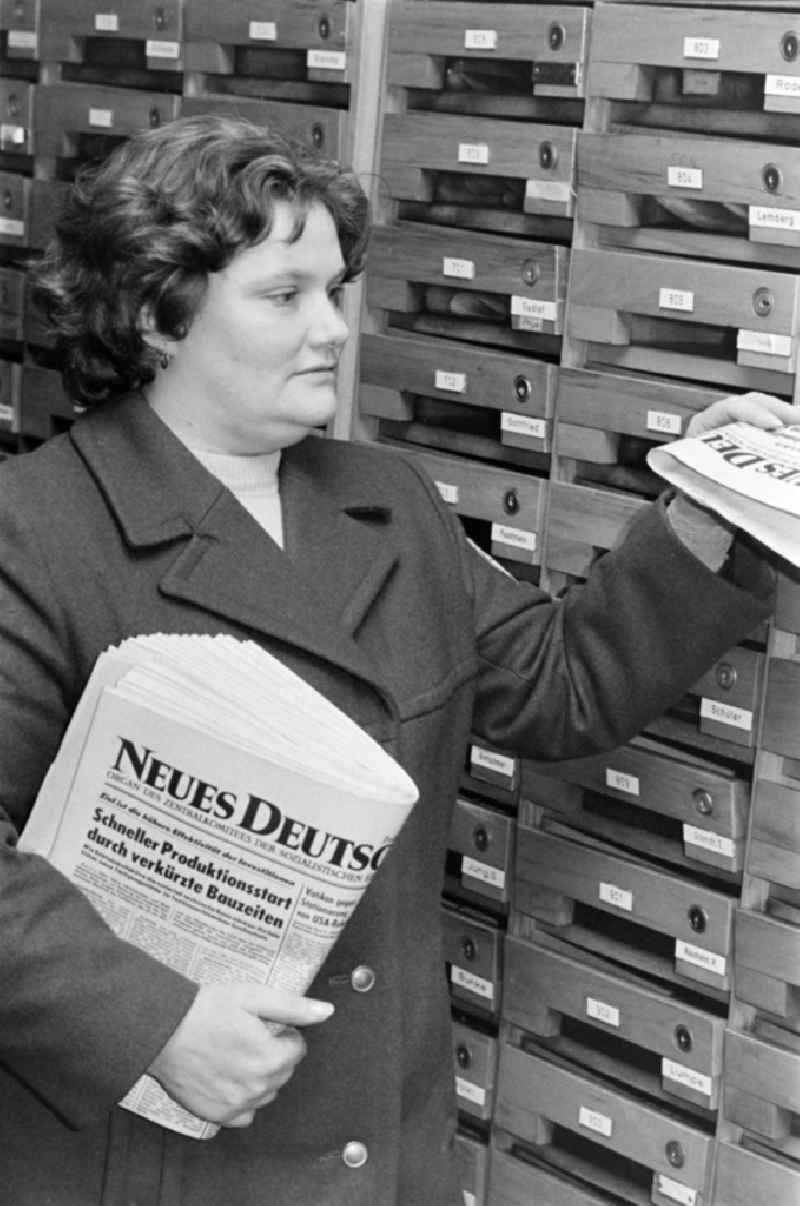 A postal woman puts the everyday newspaper 'Neues Deutschland' in mailbox of a block of flats in Berlin, the former capital of the GDR, German democratic republic