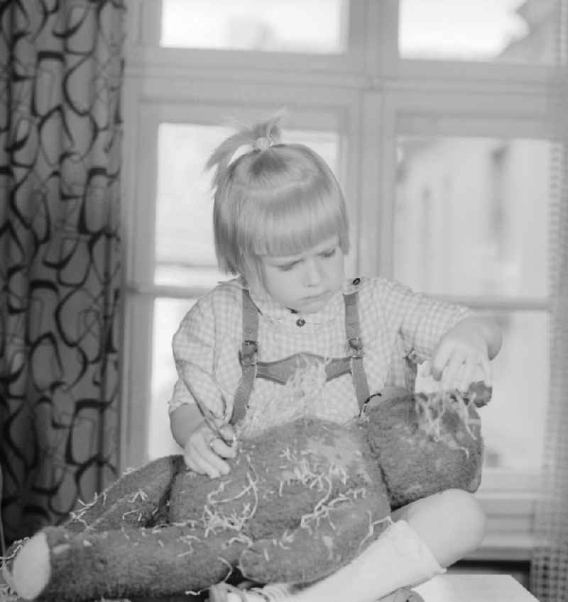 A child cuts up a teddy bear in Berlin, the former capital of the GDR, German Democratic Republic