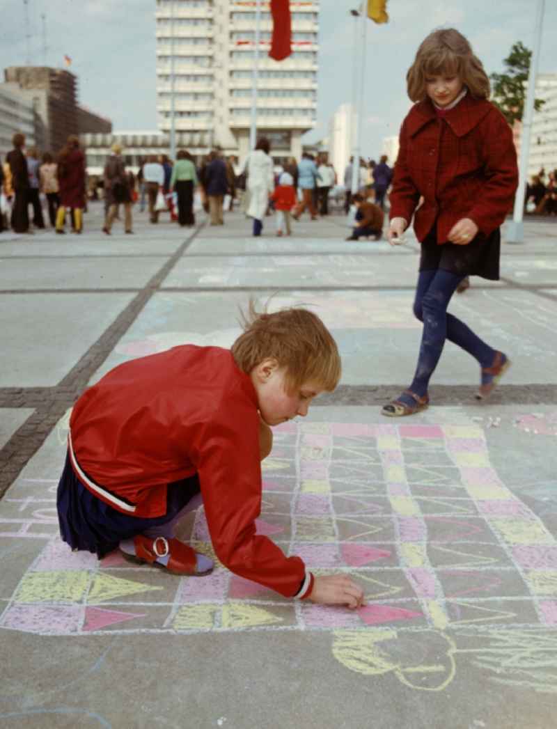 Two girls paint with chalk at the drawing competition for children on the occasion of the traditional celebrations on 1 May at Alexanderplatz in Berlin Mitte, the former capital of the GDR, German Democratic Republic
