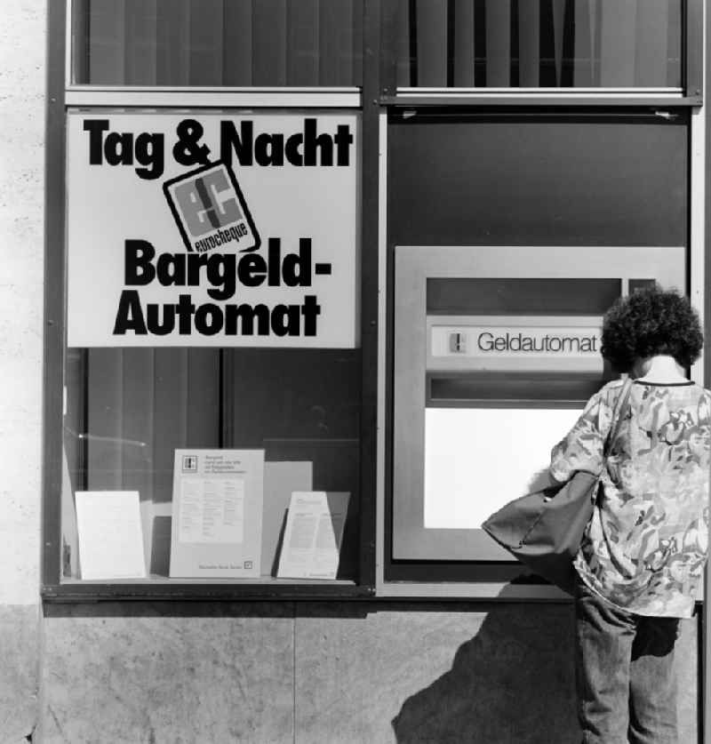 A woman collects money at the Deutsche Bank Berlin cash dispenser in Berlin