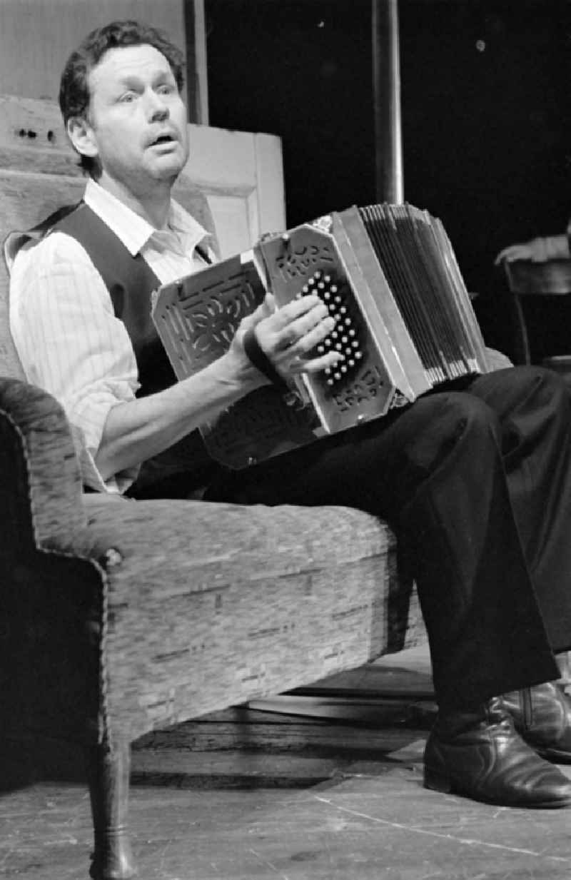 German Theatre Berlin - Berlin Songs From Then And Yesterday. Actors and performers in a theatre - scene and stage set in the Mitte district of Berlin, the former capital of the GDR, German Democratic Republic. On stage - Reimar Johannes Baur with accordion on the sofa