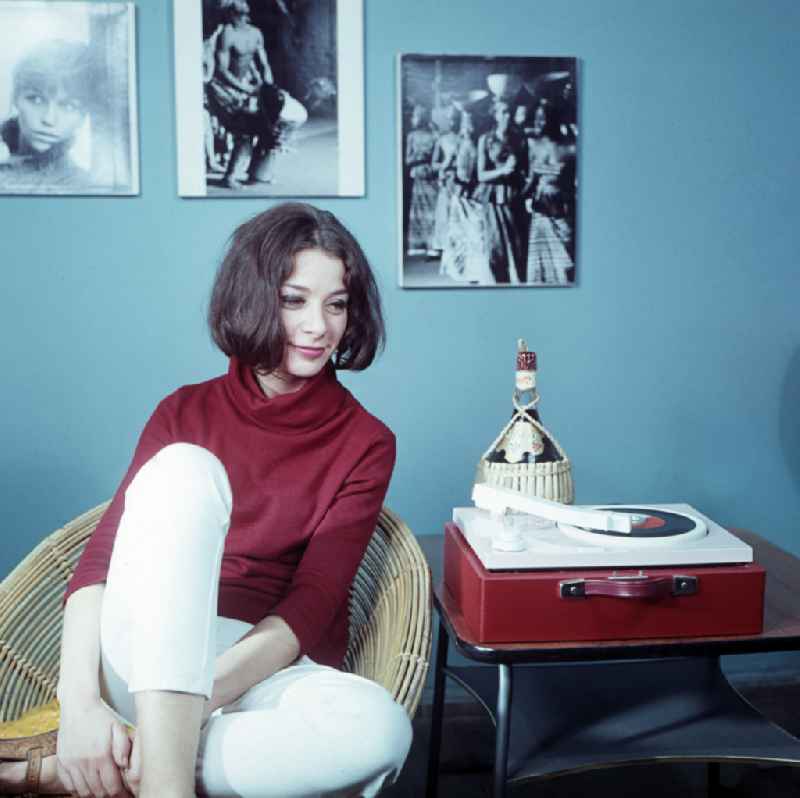 Young woman with a portable record player from VEB RFT Phonotechnik Zittau and interior design of an apartment in the Mitte district of Berlin East Berlin in the area of the former GDR, German Democratic Republic