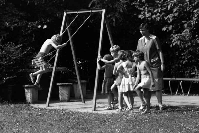 Summer temperatures while playing and having fun with toddlers cared for by educators in a kindergarten on a playground in Berlin East Berlin on the territory of the former GDR, German Democratic Republic