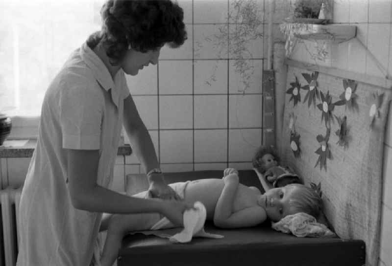 Nursery nurse in a day nursery swaddles a toddler in Berlin Eastberlin on the territory of the former GDR, German Democratic Republic