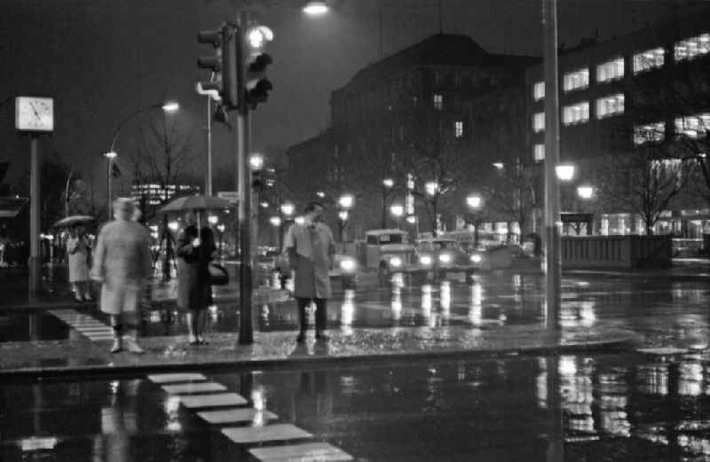 Pedestrians and passers-by in traffic in the night rain on street Friedrichstrasse, Ecke Unter den Linden in Berlin Eastberlin on the territory of the former GDR, German Democratic Republic