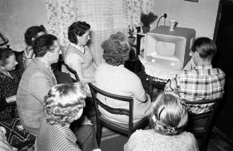 Women and men in the evening in front of a television set of the brand Stern Radio Berlin 'Weissensee' in the district of Koepenick in Berlin East Berlin in the area of the former GDR, German Democratic Republic