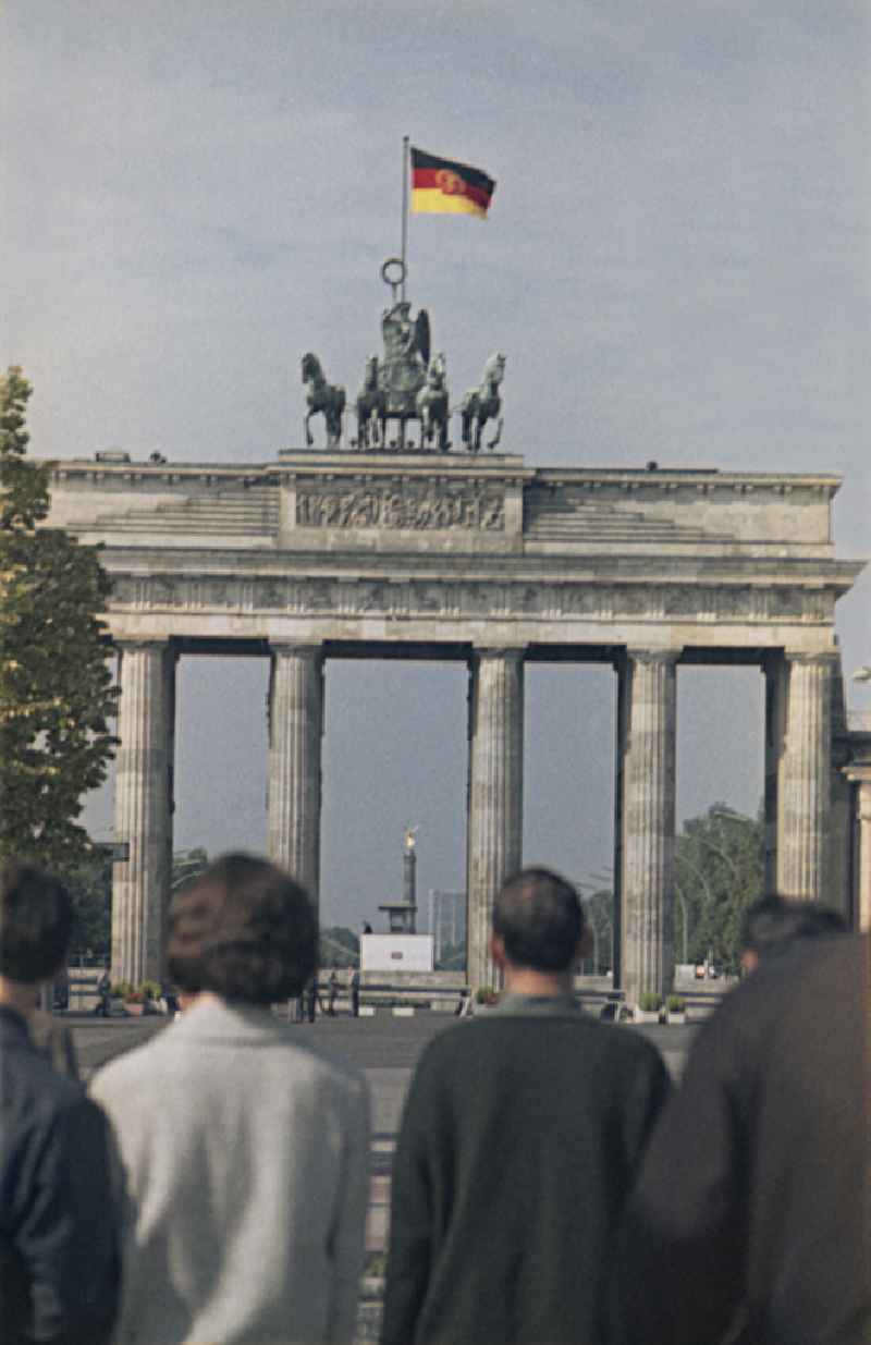 Tourist attraction and landmark Brandenburg Gate with Quadriga and GDR flag in the border area of the Wall and state border at Pariser Platz - Unter den Linden in the Mitte district of Berlin East Berlin on the territory of the former GDR, German Democratic Republic