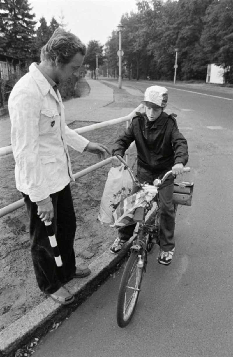 Volunteer traffic assistant of the People's Police checking the road safety of a cyclist in traffic at the intersection at Schulzendorfer Strasse and Waltersdorfer Strasse in the Bohnsdorf district of Berlin, East Berlin in the territory of the former GDR, German Democratic Republic