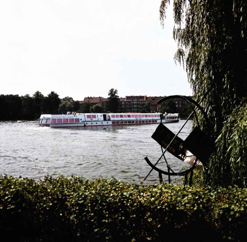 Sundial in the Luisenhain park in Koepenick in East Berlin in the area of the former GDR, German Democratic Republic. The passenger ship 'Wilhelm Pieck' of the shipping company Weisse Flotte sails on the Dahme