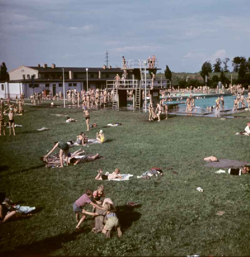 Outdoor swimming pool with sunbathing lawn, swimming pool and diving tower on the street Sportpromenade in Berlin East Berlin in the territory of the former GDR, German Democratic Republic