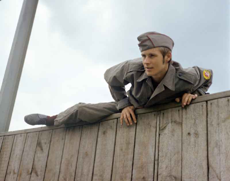 Young man overcomes an escalator wall during pre-military training on the Sturmbahn as part of the Society for Sports and Technology in Berlin, East Berlin in the territory of the former GDR, German Democratic Republic