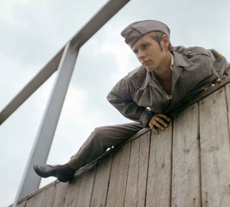 Young man overcomes an escalator wall during pre-military training on the Sturmbahn as part of the Society for Sports and Technology in Berlin, East Berlin in the territory of the former GDR, German Democratic Republic