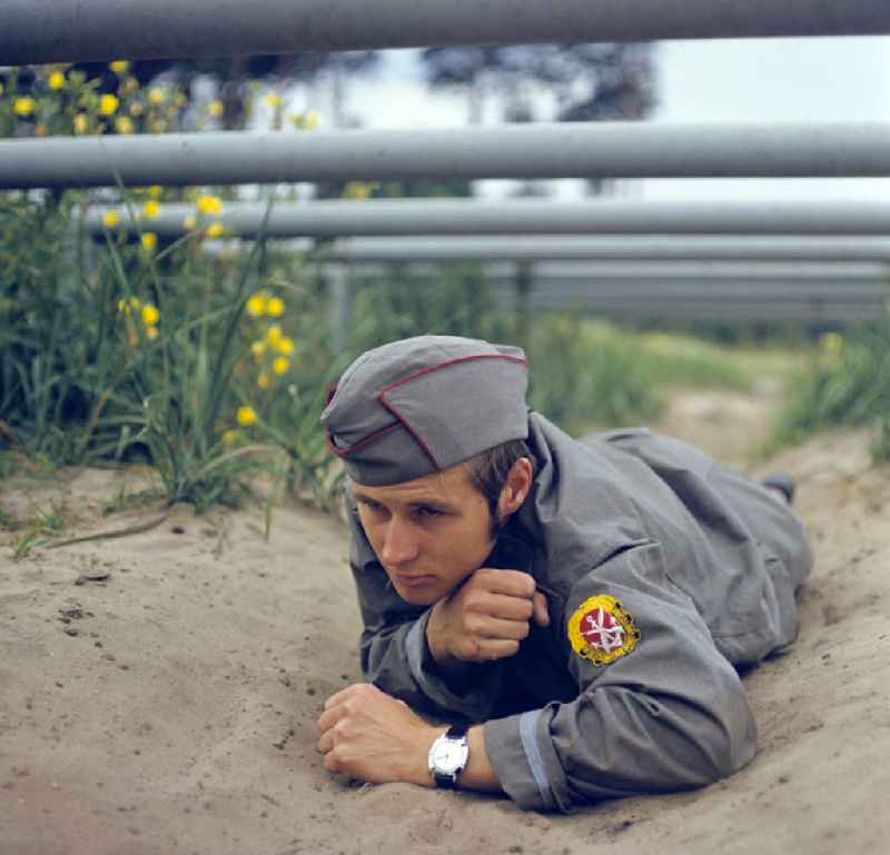 Young man overcomes a ground obstacle during pre-military training on the Sturmbahn as part of the Society for Sports and Technology in Berlin, East Berlin in the territory of the former GDR, German Democratic Republic