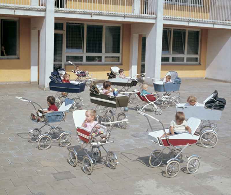 Small children sit in a stroller in the yard of a daycare center in East Berlin in the territory of the former GDR, German Democratic Republic