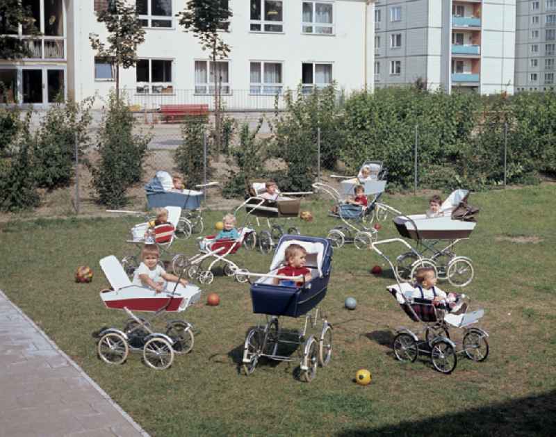 Small children sit in a stroller in the yard of a daycare center in East Berlin in the territory of the former GDR, German Democratic Republic