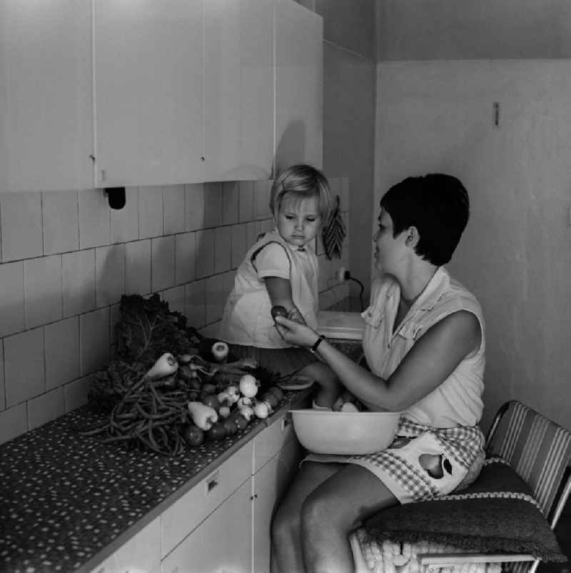 A mother sits with her child in the kitchen and dressing vegetables in Berlin - Friedrichshain
